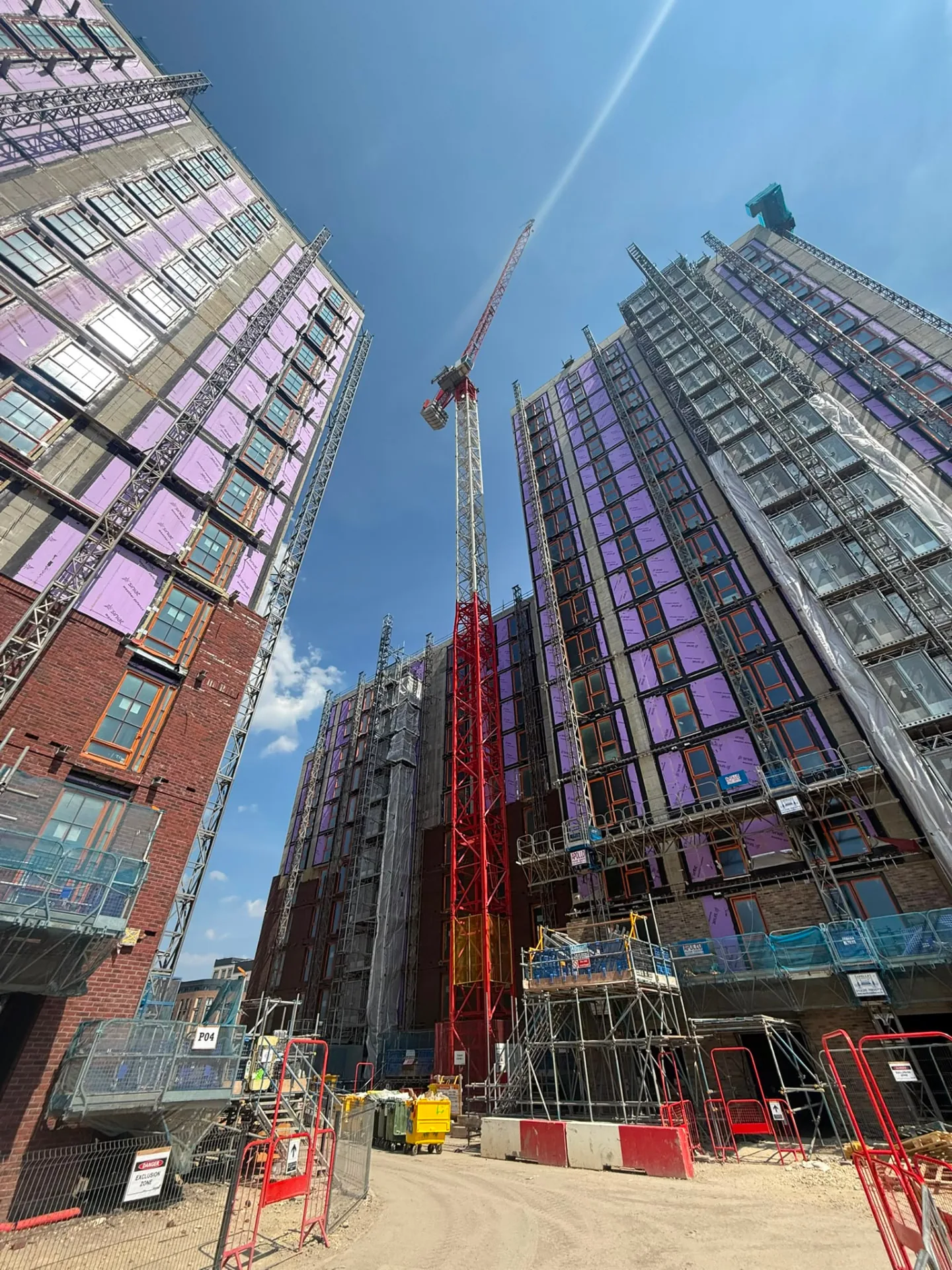 Red tower crane rising between two high rise buildings under construction
