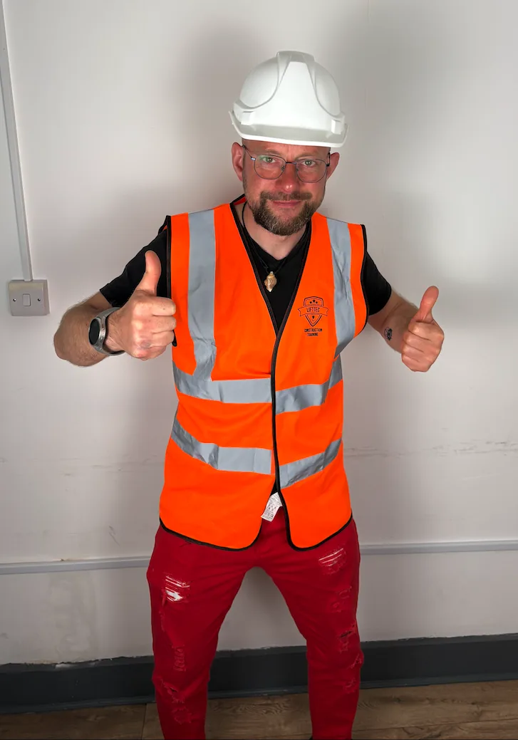 Student in a white helmet and Lift Tec hi vis vest giving two thumbs up