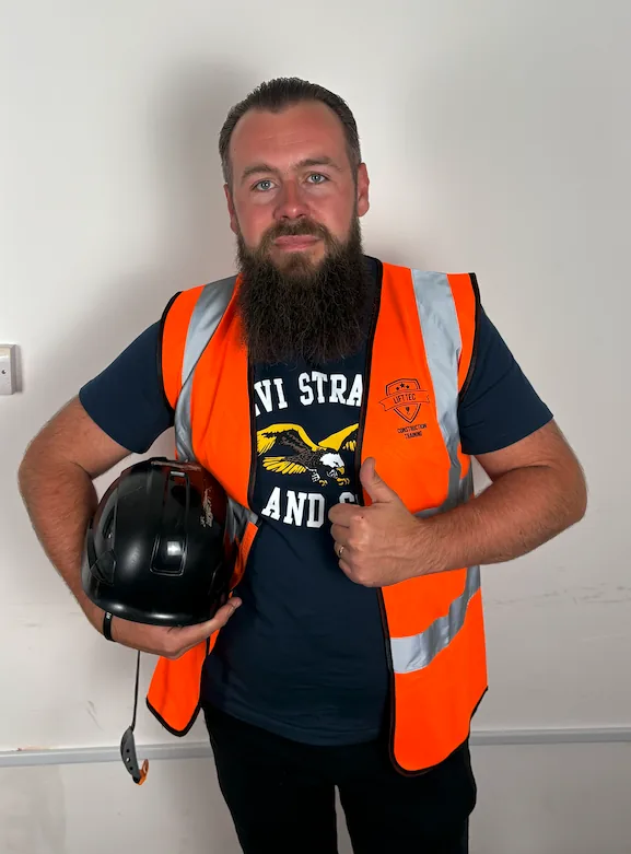 Student in a Lift Tec hi vis vest holding a black helmet