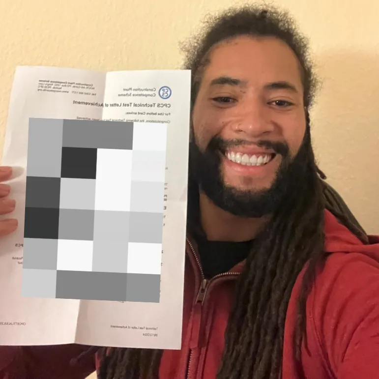 Student smiling with his CPCS technical test letter of achievement